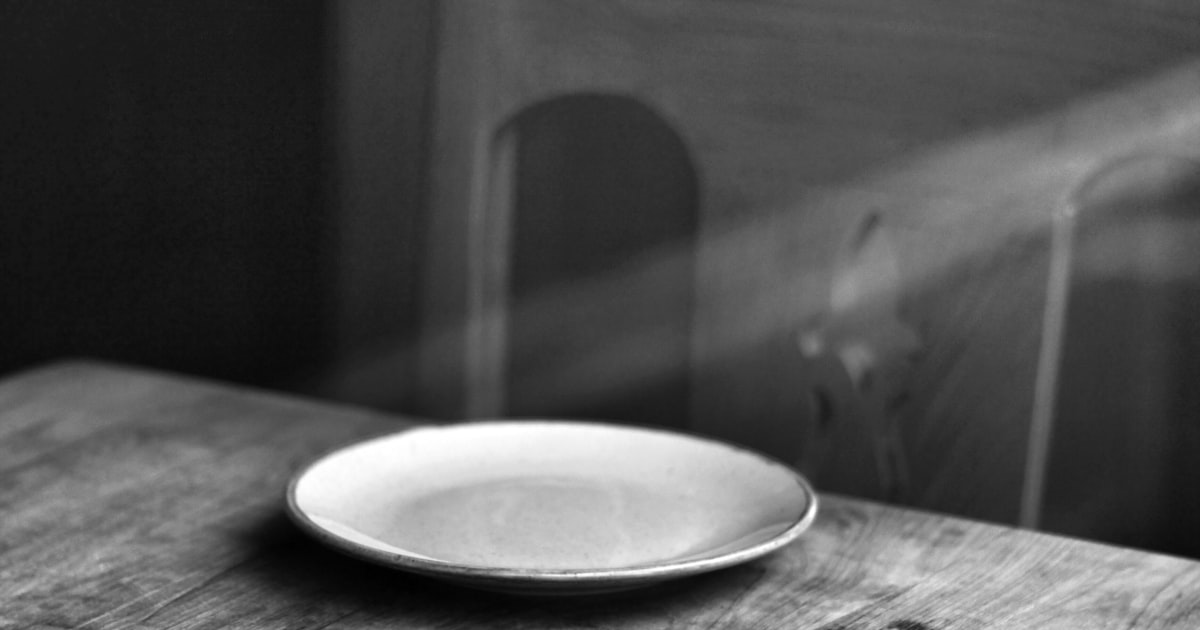 An empty plate on a bare wooden table, representing child food insecurity in Canada